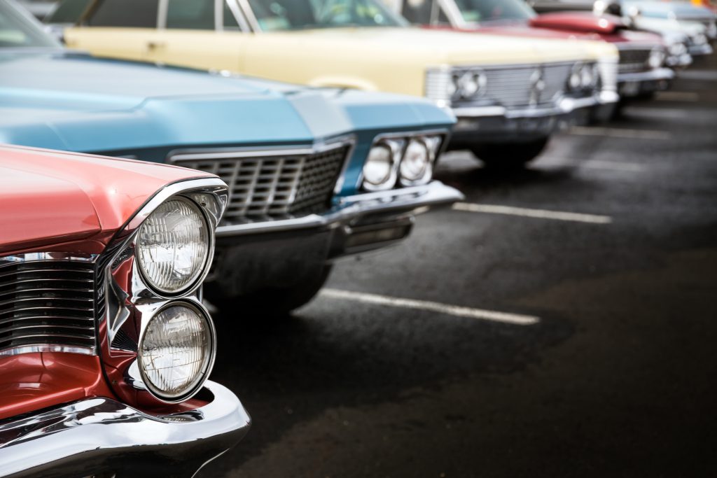 Classic cars in a row parked on asphalt parking lot