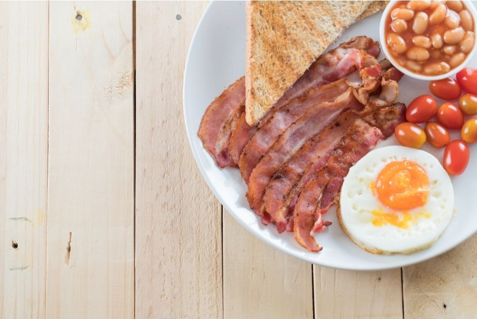 breakfast on a table showing bacon, eggs, toast