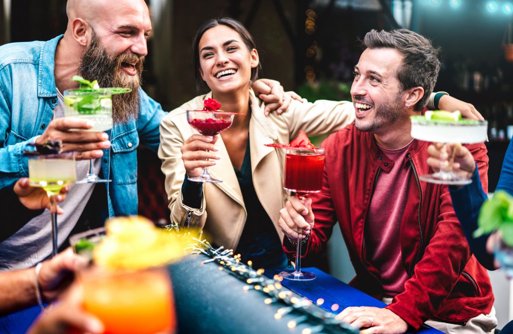 Hipster friends toasting multicolored fancy drinks at fashion bar - Trendy people having fun together drinking cocktails at happy hour - Food and beverage party time concept on vivid contrast filter