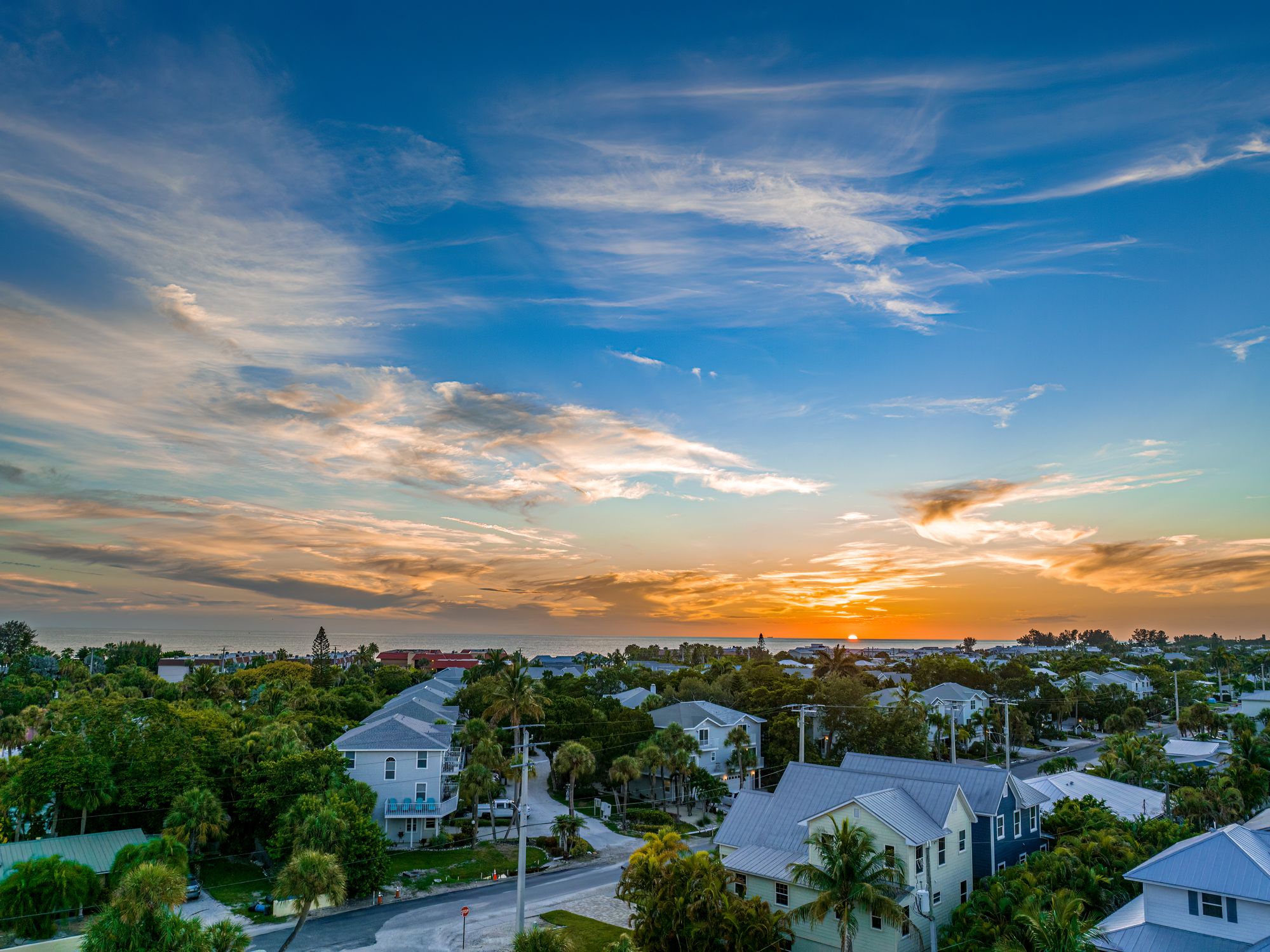 An aerial view of a a neighborhood along Holmes Beach at Anna Maria Island, Florida on a summer evening during sunset.