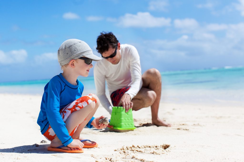 family of father and son building sand castle and enjoying summer vacation at the beach